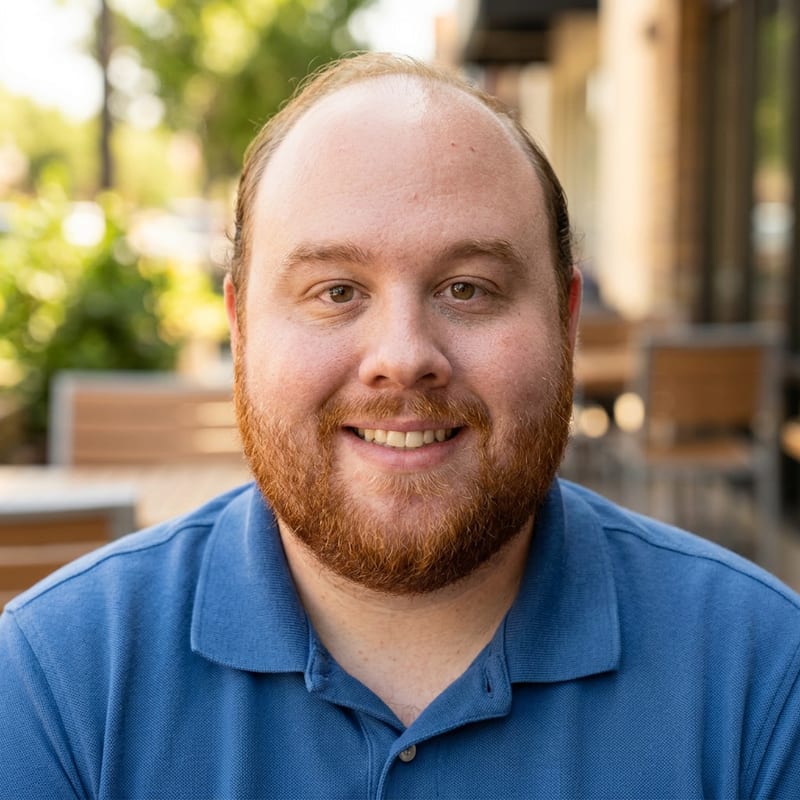 Photo of Jeffrey, a smiling man with red hair and a red beard, wearing a blue polo shirt.